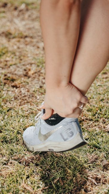 A person holding their ankle in a sneaker, indicating pain or injury.